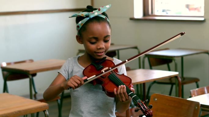 可爱的学生在教室里拉小提琴
