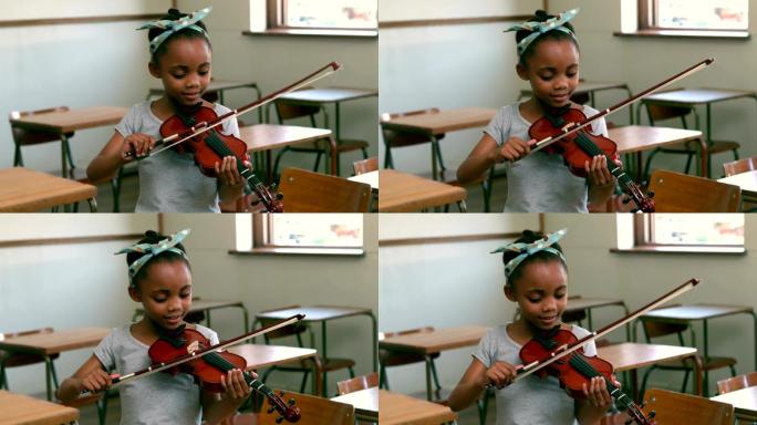 可爱的学生在教室里拉小提琴
