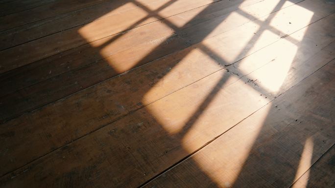 阳光透过窗户投射在旧木地板上