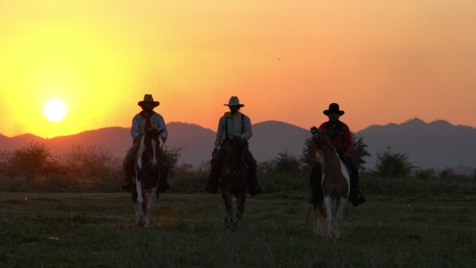 日落时骑着马匹的牛仔