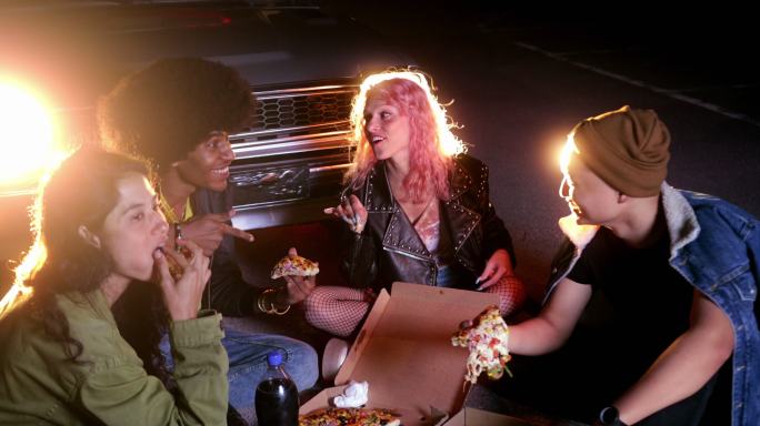 朋友们晚上在停车场吃外卖比萨饼