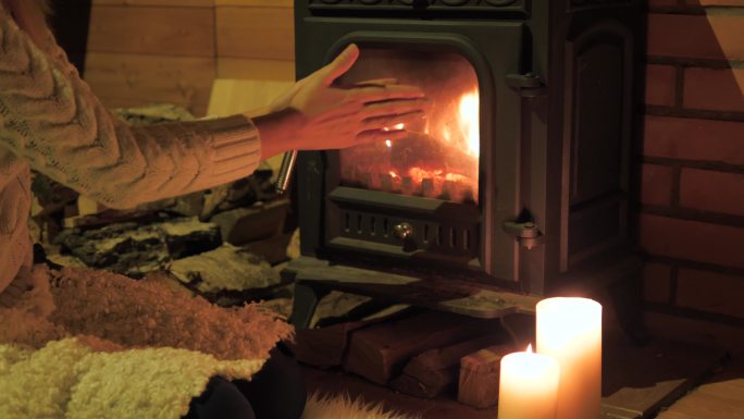 特写镜头女人在炉火旁暖手