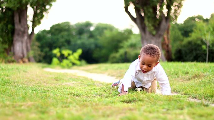 可爱小男孩在草地上玩耍和爬行