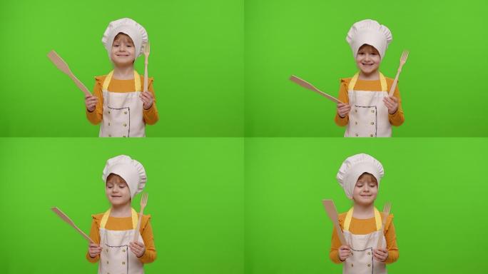 打扮成厨师的小女孩展示着木叉和抹刀