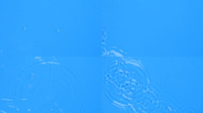 蓝色水滴落到蓝色墨水的液体表面。