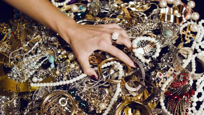 女性触摸着一堆金银珠宝。