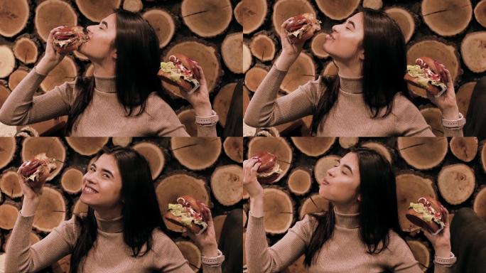 一位饥饿的年轻女子微笑着吃汉堡的特写镜头