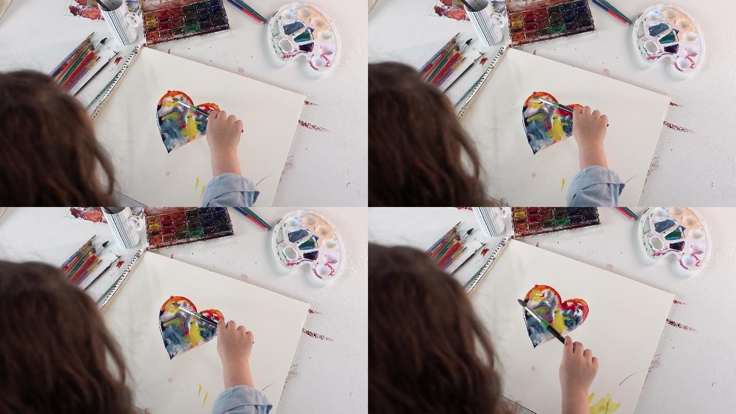 小孩正在白纸上画彩色的心。