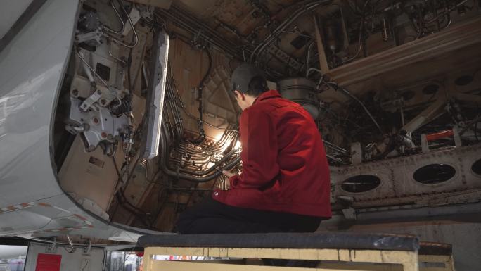 工程技术员用手电筒检查飞机内部。