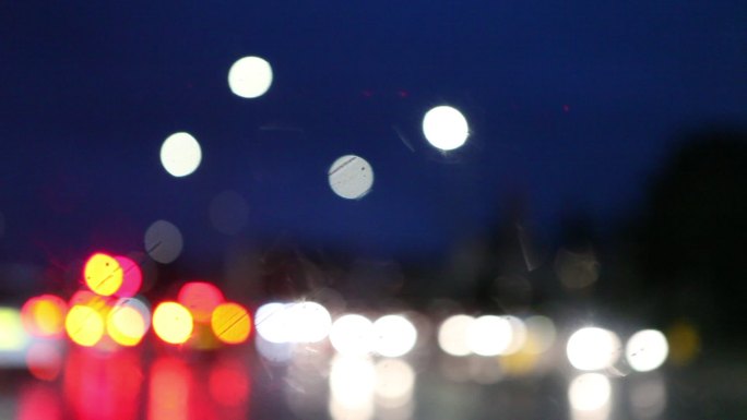 在雨中行驶的汽车在夜间穿过城市