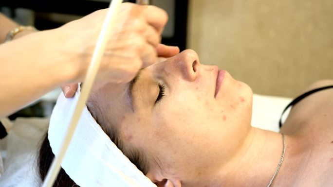 美容师为年轻患者使用设备进行皮肤面部清理