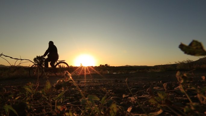 夕阳下骑自行车赶路的男人