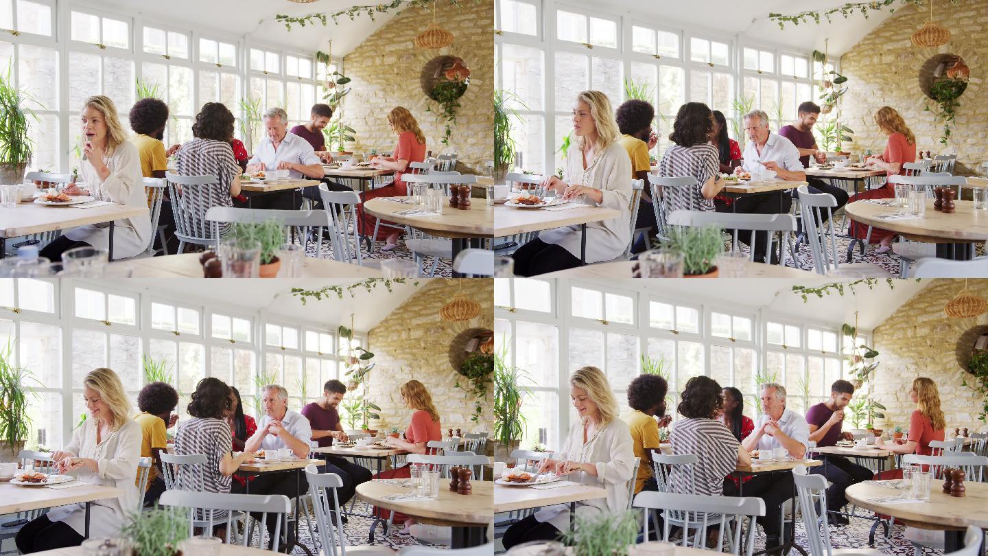 在餐厅里，顾客们坐在桌子旁吃饭