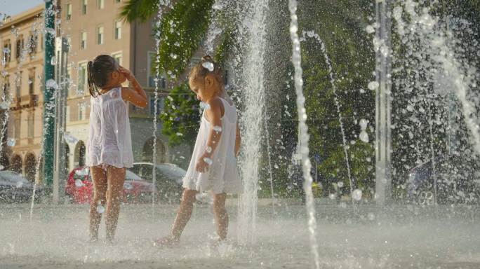 两个小女孩在喷泉里玩得很开心