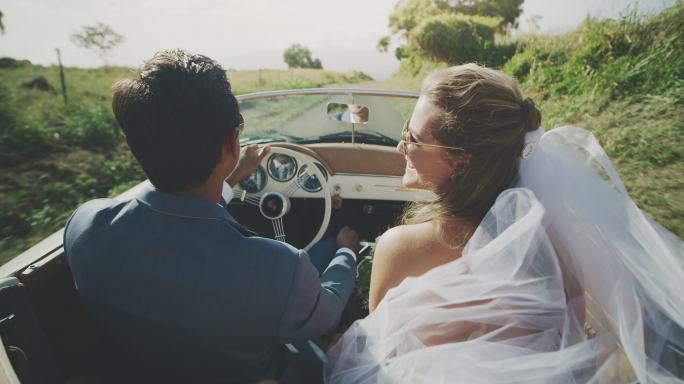 幸福的新婚夫妇在乡村公路上开车