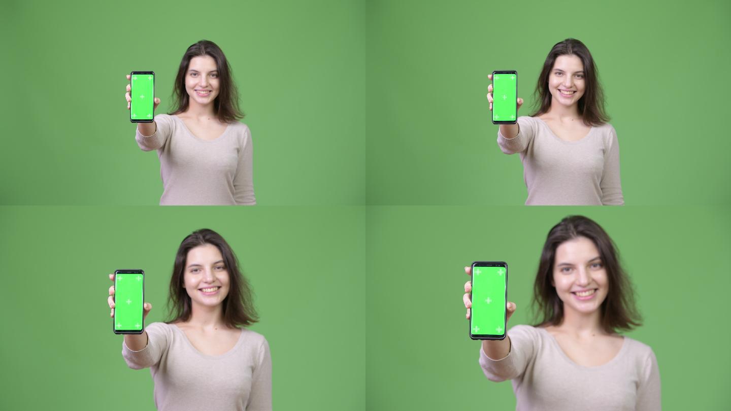 美女在绿色背景下展示手机