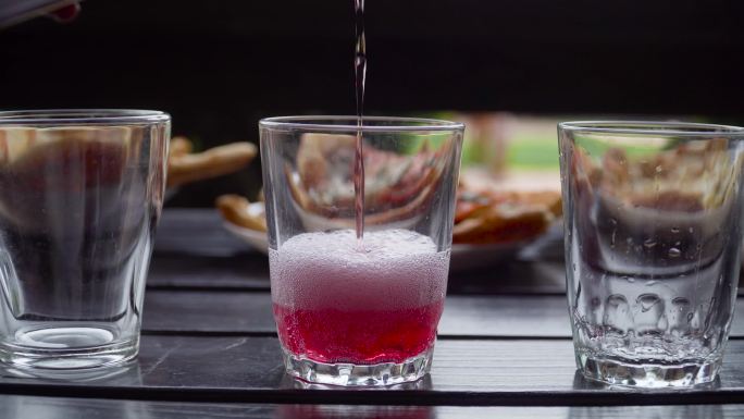 粉红色的苏打水倒进玻璃杯