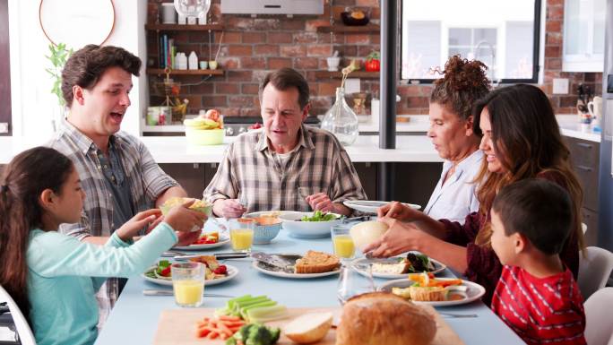 几代人的家庭围坐在家里的餐桌旁享受着美食
