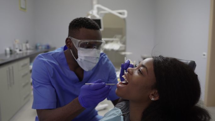 牙医在牙科诊所检查年轻女性患者的牙齿