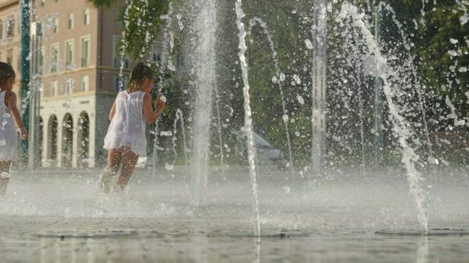 两个小女孩在喷泉里玩耍