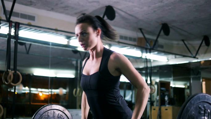 在锻炼的女人健身房器械力量训练杠铃举重