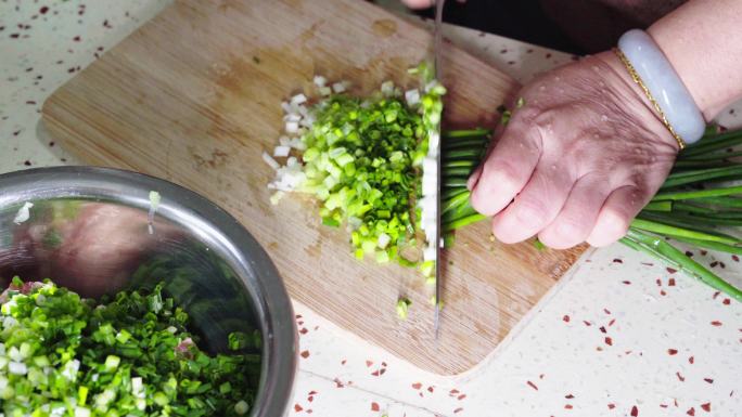 一位厨师在切细葱花，准备做包子的馅料