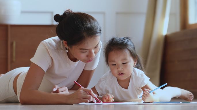 妈妈帮助小女儿用铅笔画画