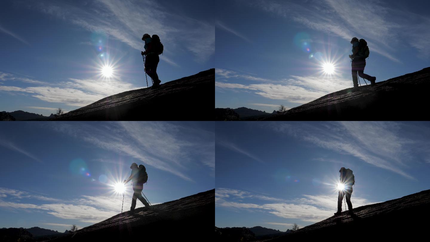 夕阳映衬下的徒步旅行者下山的剪影