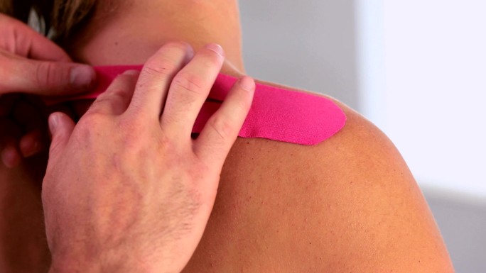 物理治疗师在患者背部使用粉色运动带