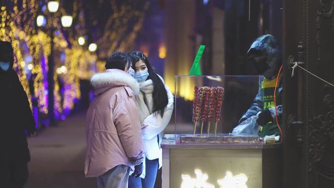 哈尔滨中央大街下雪冬夜美女游客买冰糖葫芦