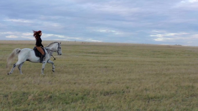 骑着白马的骑手。草原丘陵山坡骑手西部牛仔