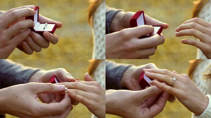 男子将银订婚戒指戴在女子手上，在秋季公园求婚