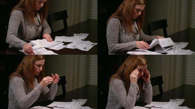 一个女人看着桌上的账单，看起来很烦恼