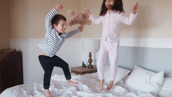 床上玩耍的小孩子姐弟开心蹦跳