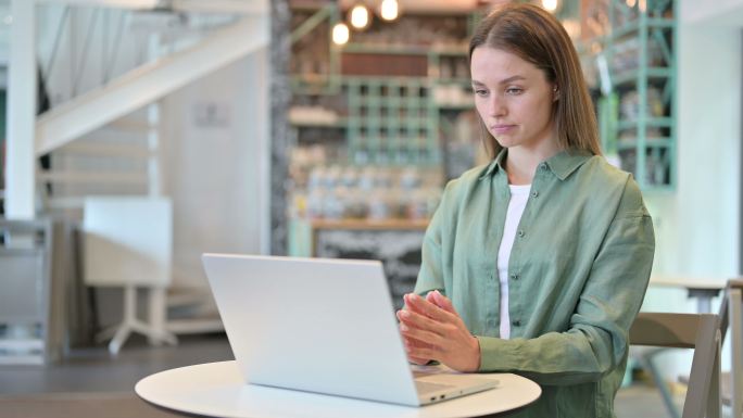 在咖啡馆用电脑思考和工作的女人