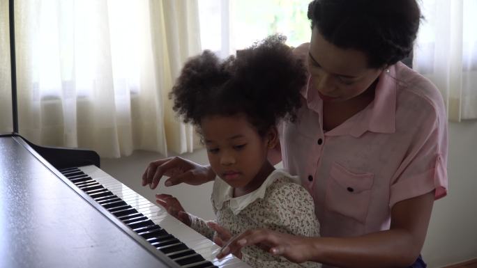 母亲教女儿在家里弹钢琴。