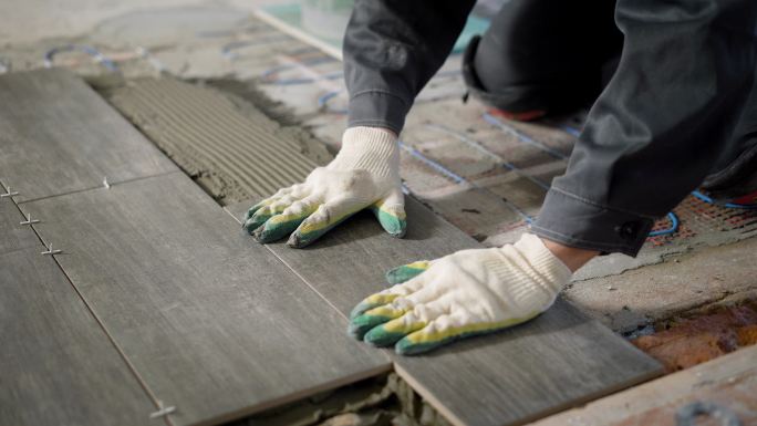 工人正在水泥和地板装置上方安装瓷砖地砖