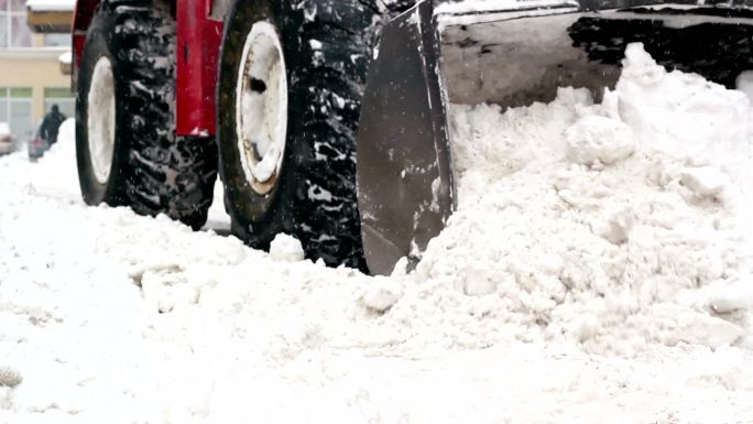 轮式装载机的铲斗铲走街道上的积雪