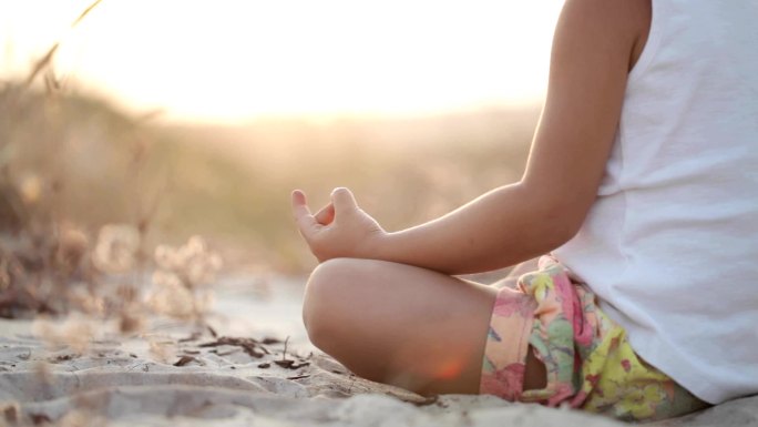 小女孩在日落时坐在沙滩上