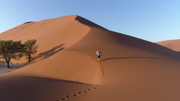 沙漠中行走的男人徒步探索孤独独行脚印
