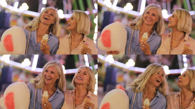 老年妇女在游乐场吃冰淇淋和玩得开心