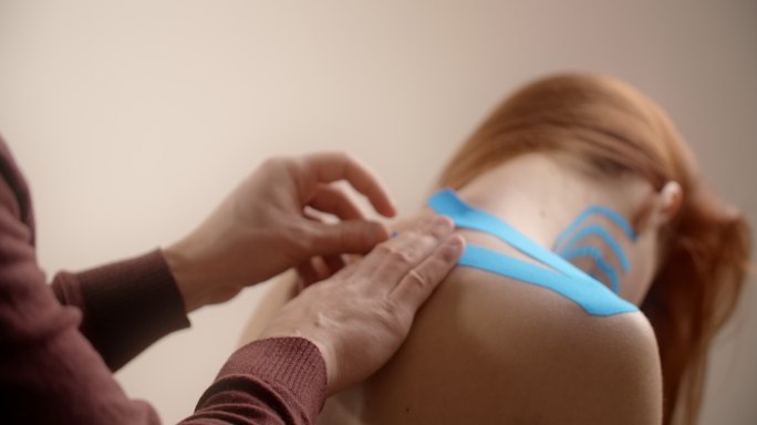 运动学家将胶带粘在女性患者的脖子上