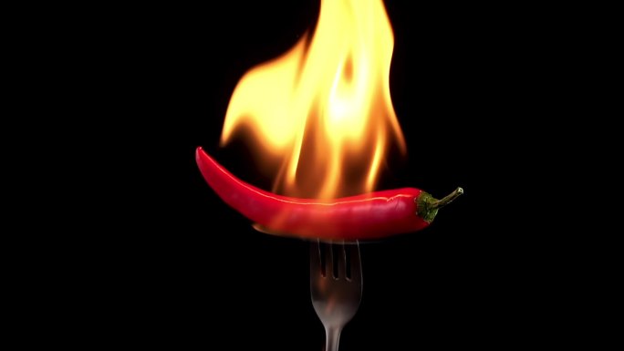 叉子上的红辣椒在火焰中燃烧