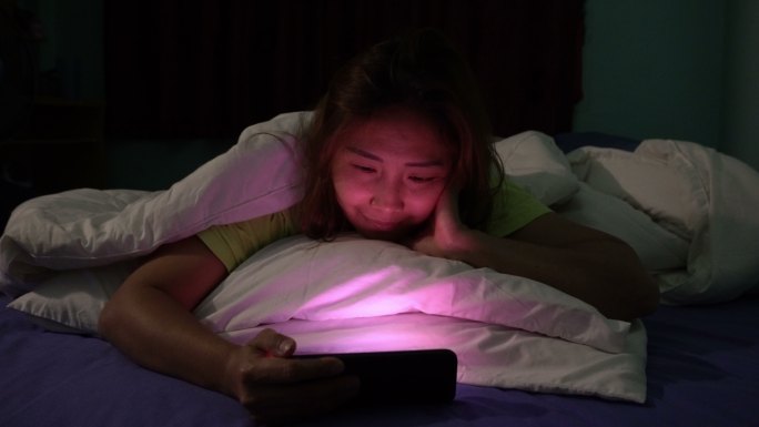女人晚上在床上玩智能手机