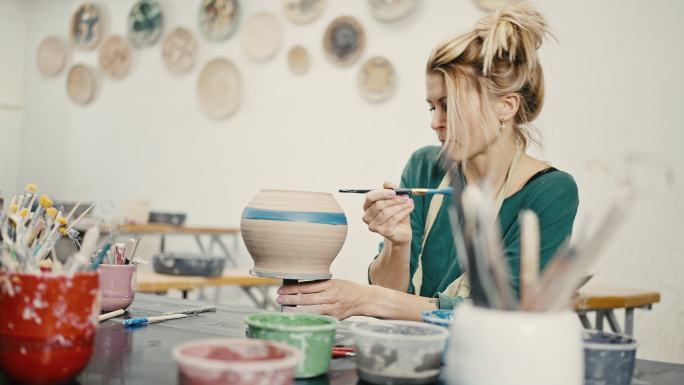 女人在艺术工作室用画笔画陶瓷壶