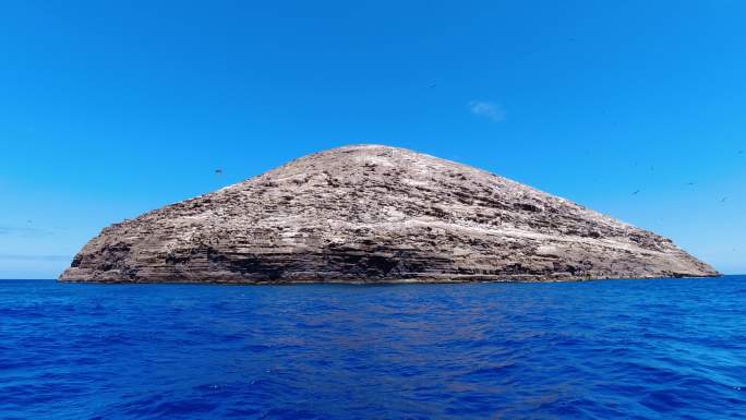 在蔚蓝的大海上航行经过光秃秃的火山岛
