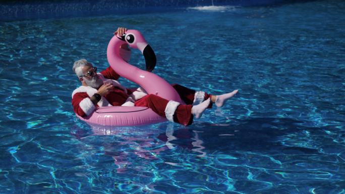 游泳池里的圣诞老人漂浮在充气环里
