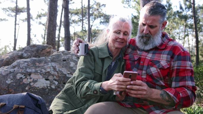在森林里用智能手机的老年夫妇