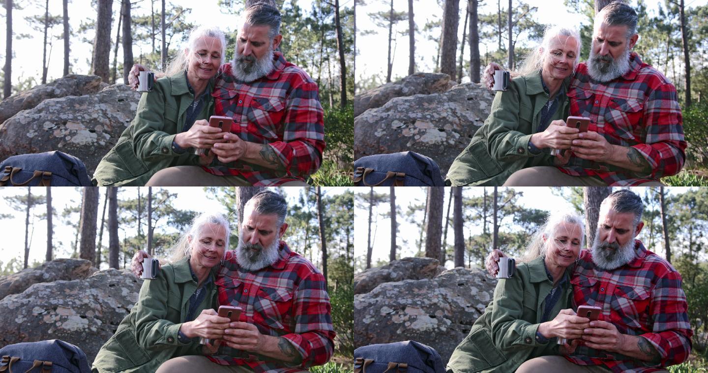 在森林里用智能手机的老年夫妇