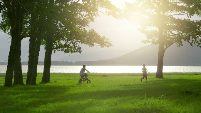 两个小男孩在草坪上骑自行车和跑步